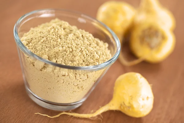 Maca powder (flour) in glass bowl with maca roots or Peruvian ginseng (lat. Lepidium meyenii) 