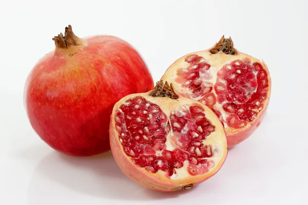 Whole and half pomegranate with seeds on white 